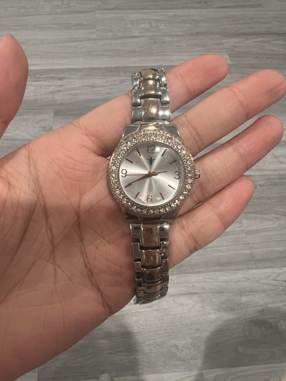 This silver and rose gold-toned women’s wristwatch features a crystal-encrusted